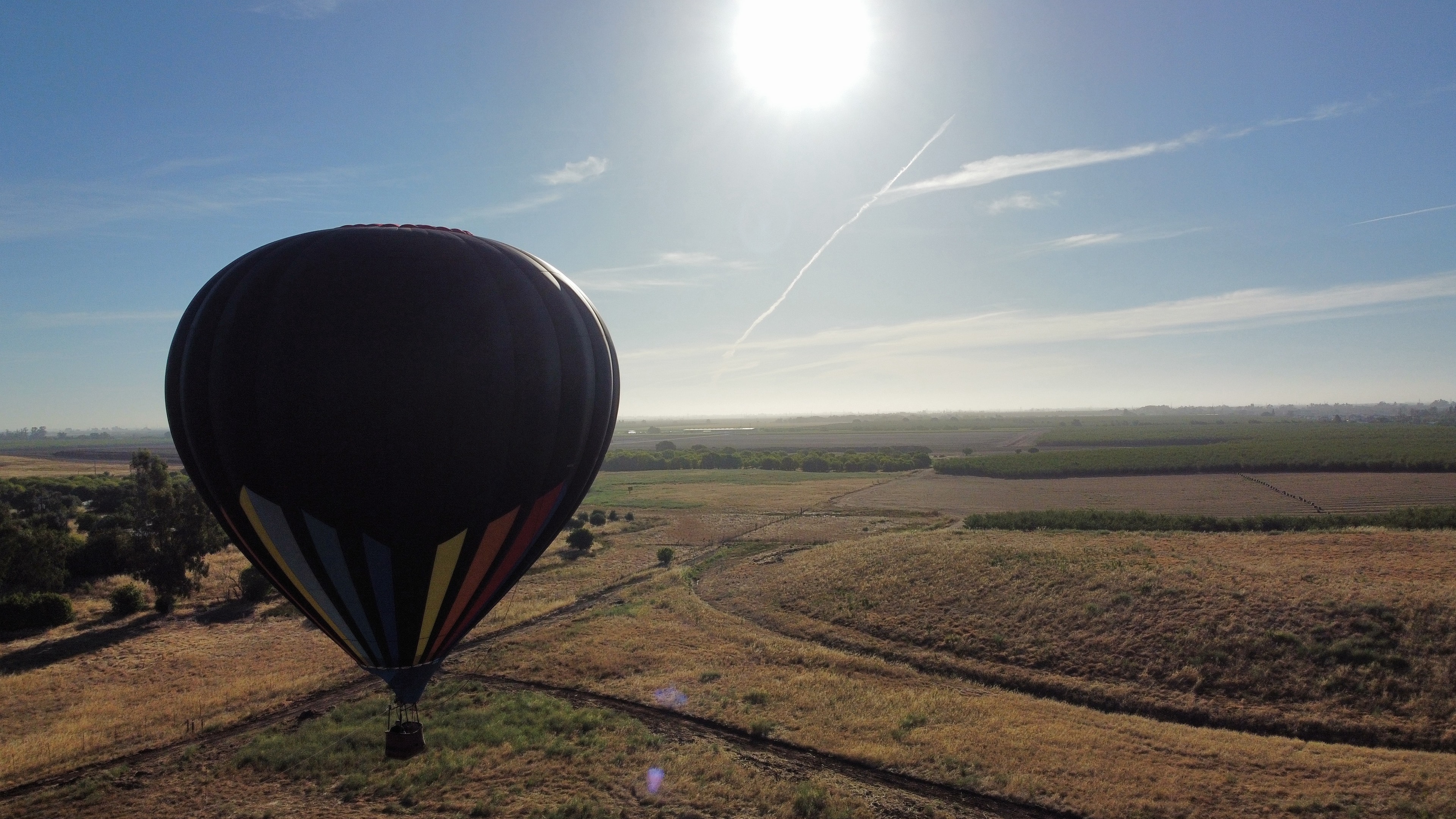 Uplift Ballooning hot air balloon soaring over open fields